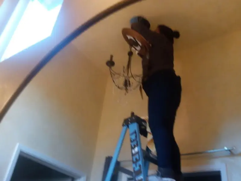 Electrician installing a chandelier in a Ray residence